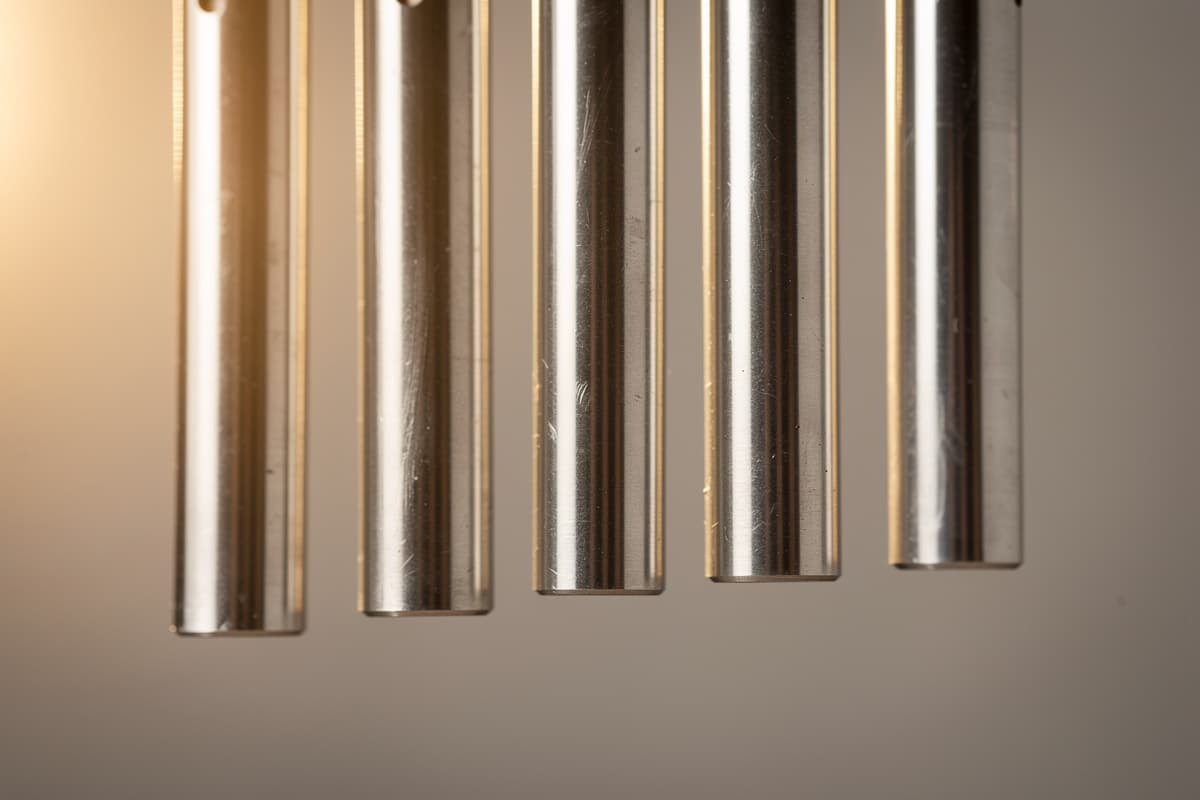 Close-up of wind chime tubes of different lengths with soft light, suggesting different musical intervals and harmonics